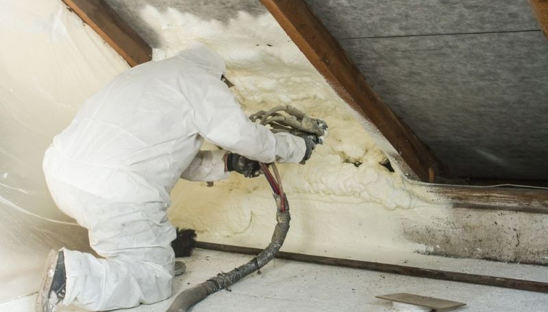 a man in suit spraying icynene on the wall forming a foam as alternative insulation